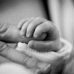 Foto de un bebé cogiendo con fuerza la mano de su madre